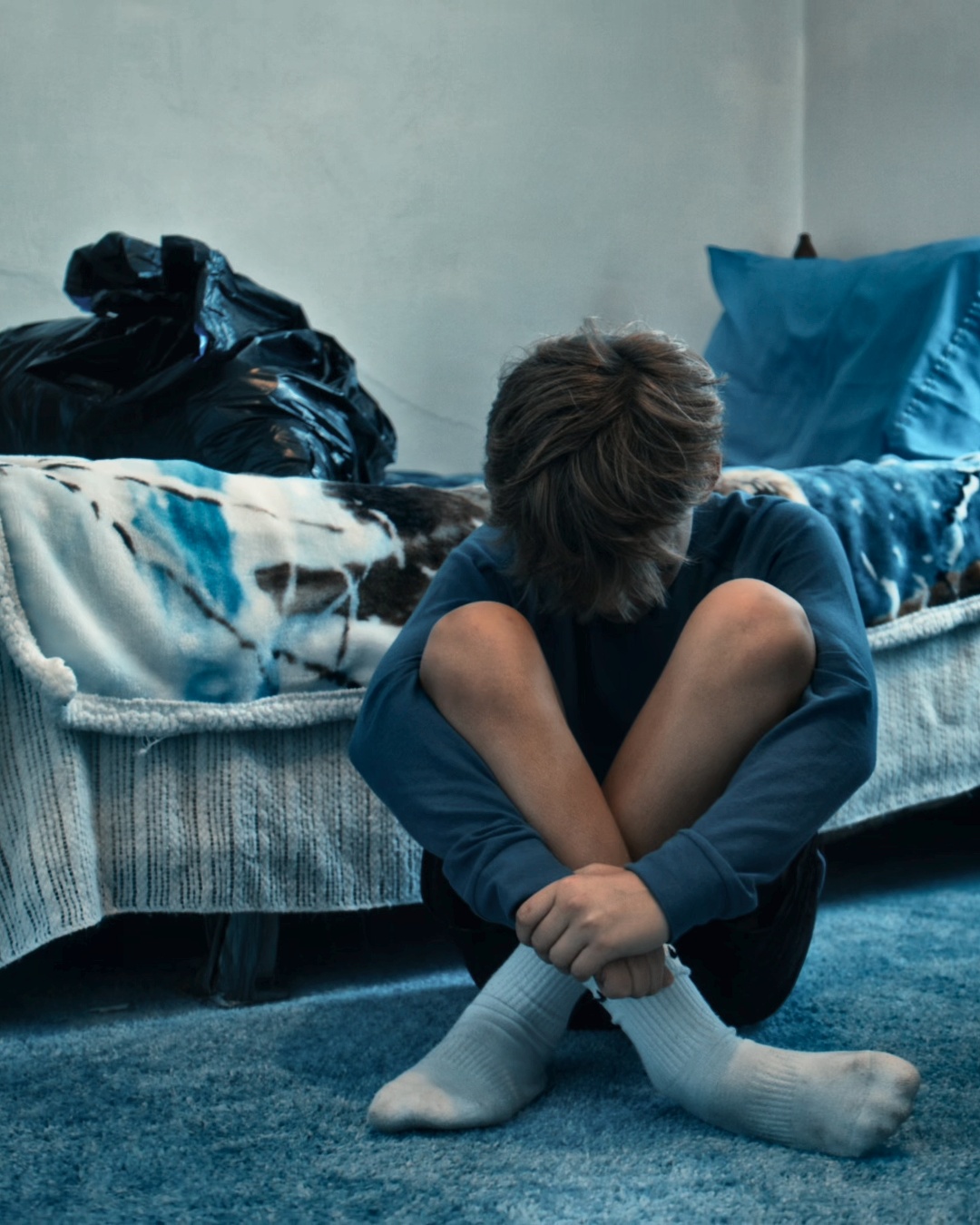 A boy sitting on a bed in a new room